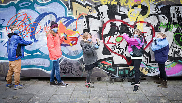 Kinder stehen vor einer Graffiti Wand 