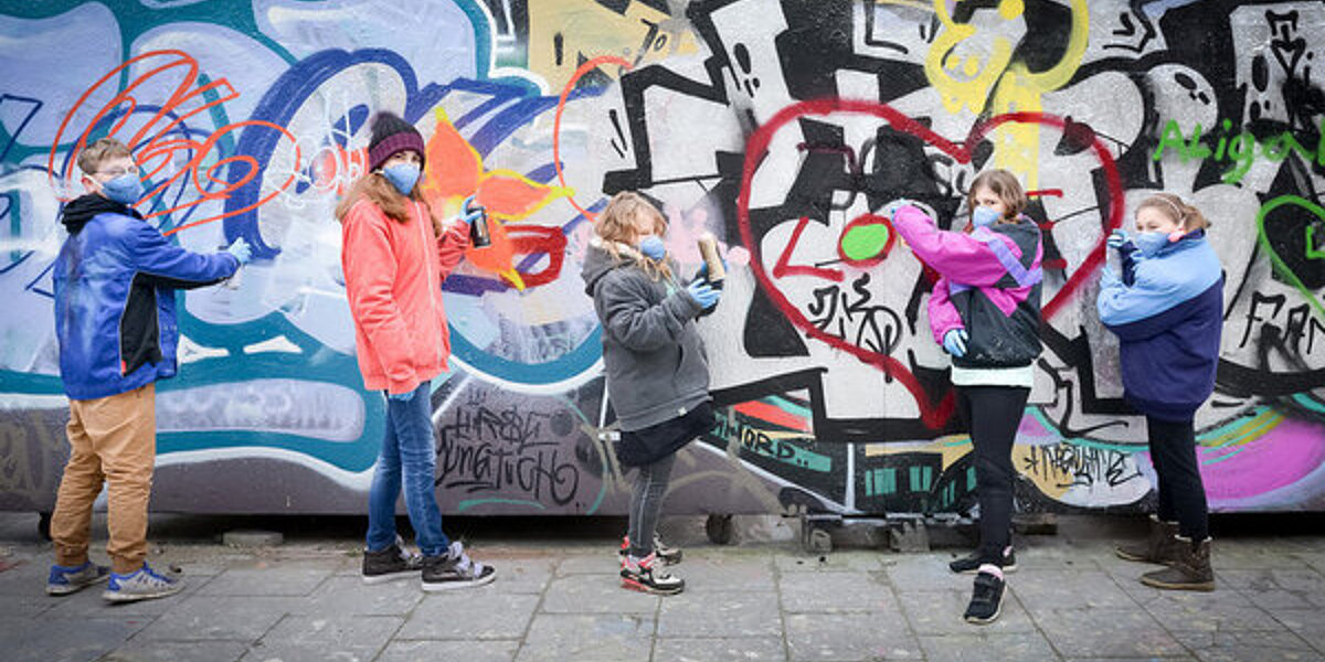 Kinder stehen vor einer Graffiti Wand 